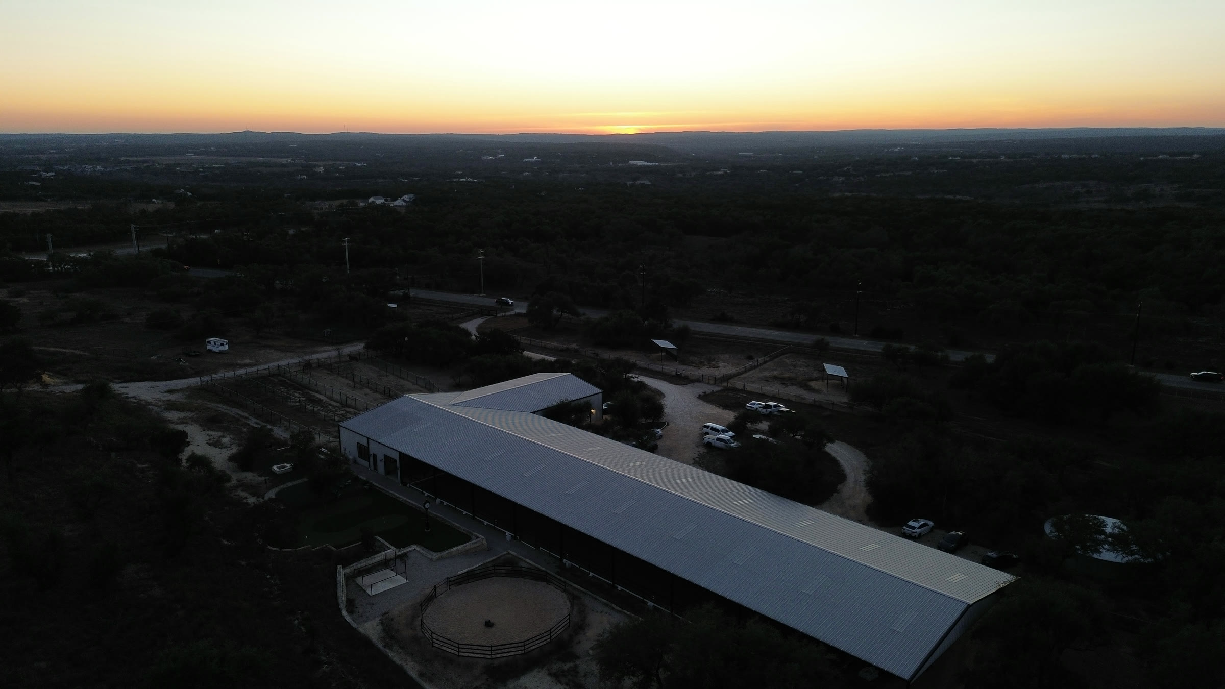 The barn from high above at sunset, with the Texas Hill Country stretching to the horizon