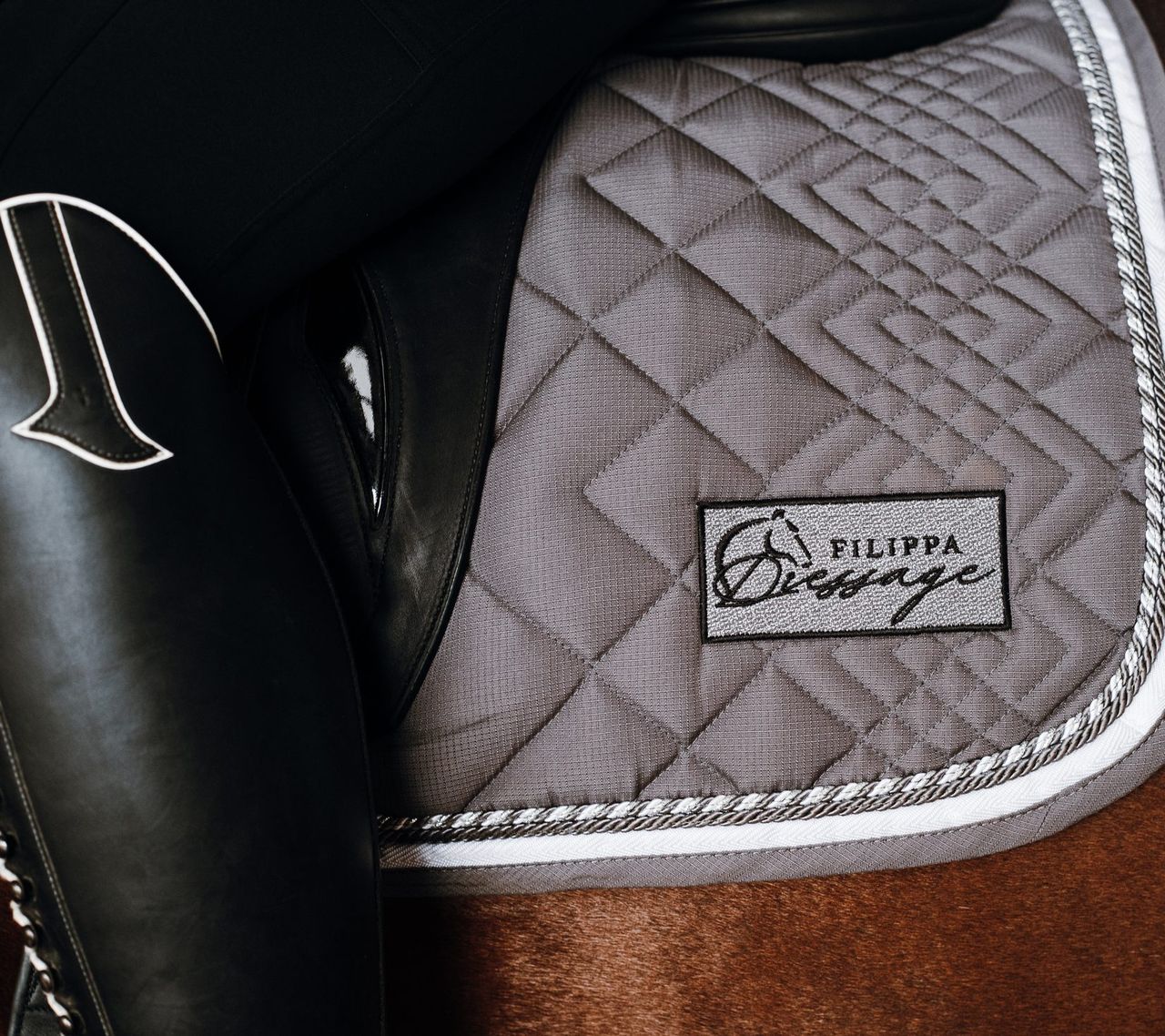 A black dressage saddle over a quilted Filippa Dressage saddle pad